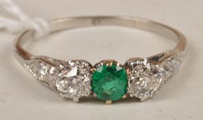 An Edwardian diamond and emerald ring, the central round cut emerald flanked on both sides by
