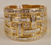 A diamond ring, the gold coloured wide shank set with square and round cut diamonds in a basket