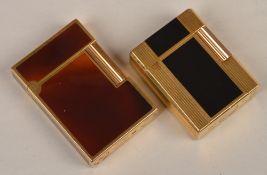 Two cigarette lighters by Dupont, one with black enamel vetical band with fluted sides, the other