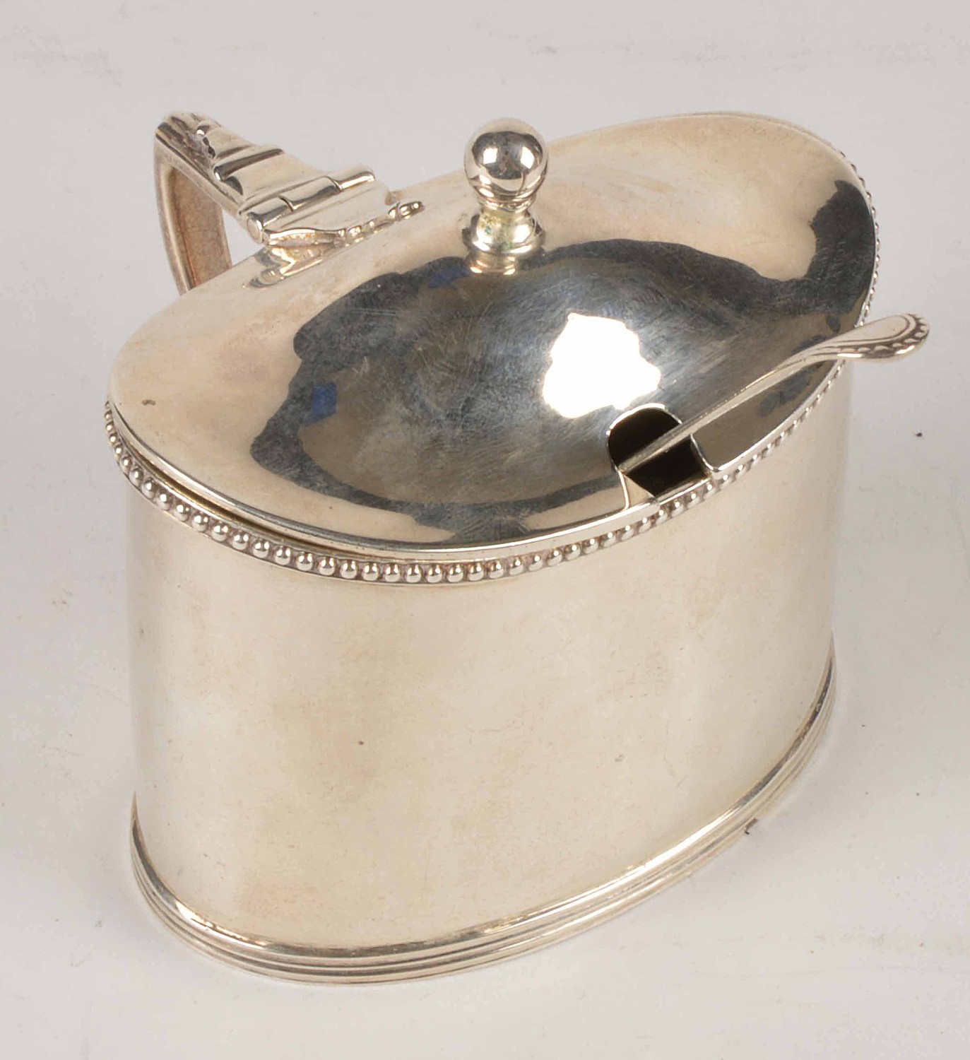 A Victorian silver oval mustard pot by Charles Boyton, London 1886, with a ball finial, a beaded