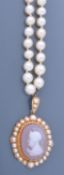 A hardstone cameo pendant and cultured pearl necklace, the oval hardstone cameo carved to depict