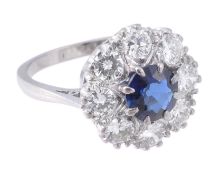 A sapphire and diamond cluster ring, the circular shaped sapphire, approximately 1 carat, claw set