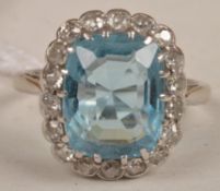 An aquamarine and diamond cluster ring, the rectangular cushion shaped aquamarine with a surround