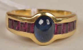 A sapphire and ruby ring, the oval cabochon sapphire, with four calibre cut rubies to either side,