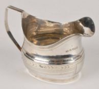 A George III silver oval cream jug, maker`s mark `I. M`, London 1814, with a harp handle, a reeded