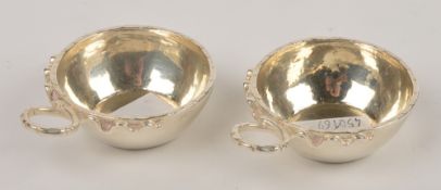 A pair of French silver coloured wine tasters, the plain bowls with embossed rim and looping ribbon