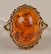 A 9 carat gold and amber ring, the cabochon amber open set with a twist design and bead work