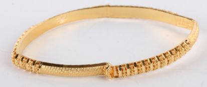 * An Indian bangle, stamped `22K`, of hollow D section, with diamond cut decoration,5.5cm internal