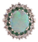 An opal, emerald and diamond cluster ring, the central oval opal cabochon claw set above a surround