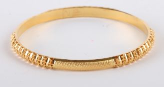 * An Indian bangle, stamped `22K`, of hollow D section, with diamond cut decoration,5.5cm internal