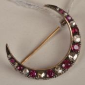 An Edwardian ruby and diamond crescent brooch, the alternating round cut rubies and rose cut