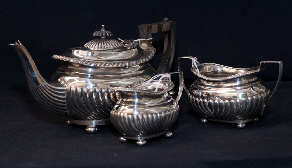 A late Victorian silver three piece tea set, comprising tea pot, milk sugar and twin handled