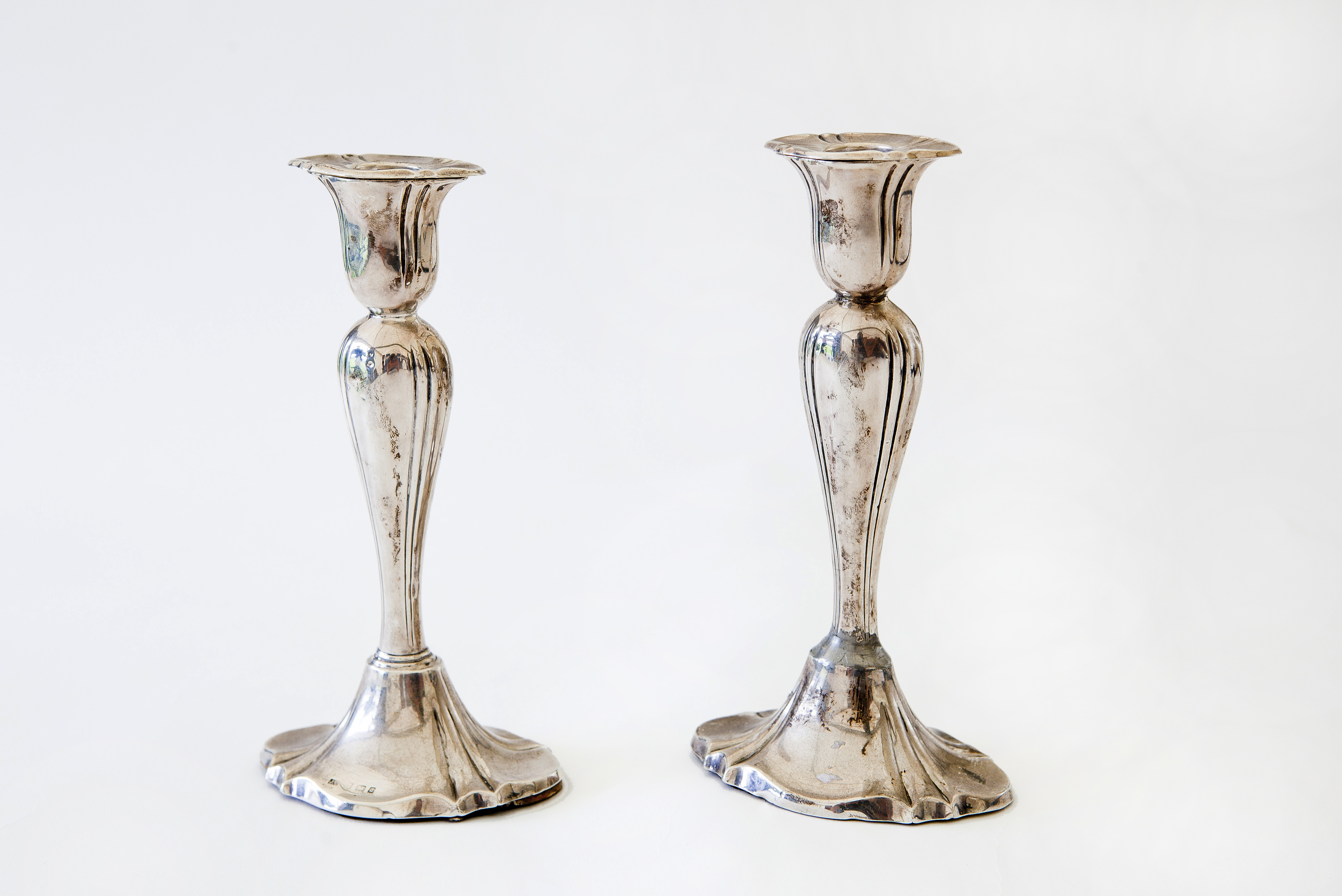 A pair of Edwardian silver candlesticks, the waisted stems on flared oval bases, 20cm high, loaded