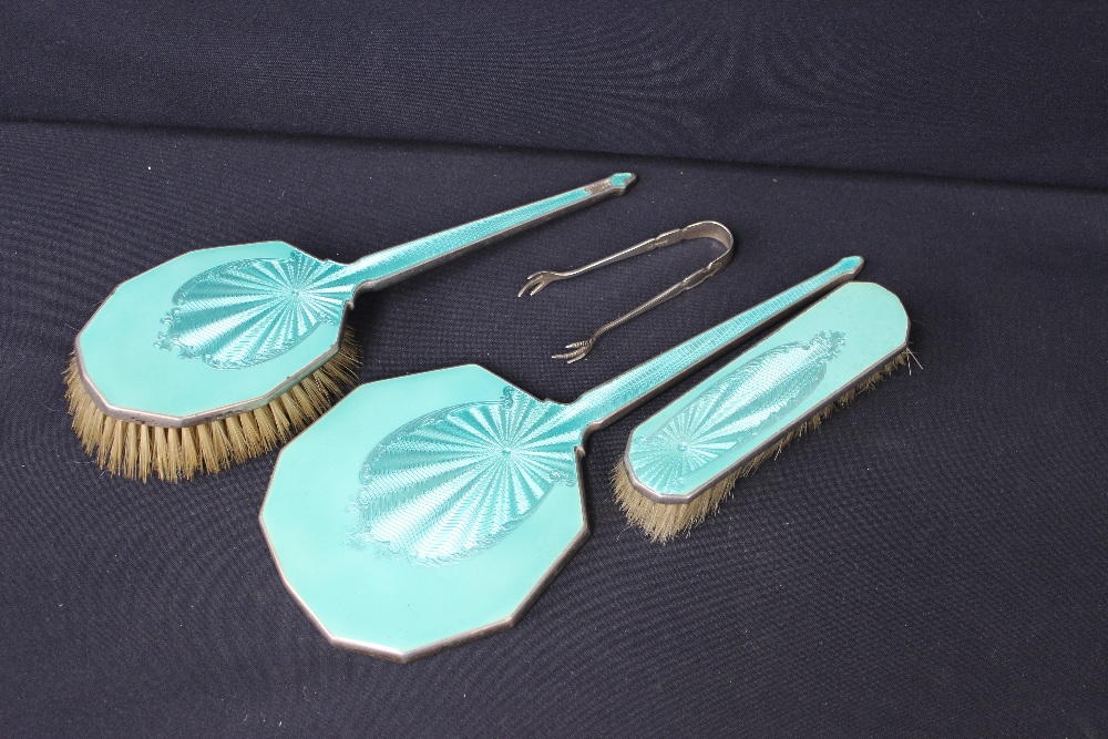 A silver and enamel three-piece dressing table brush set; a pair of silver sugar nips (4)