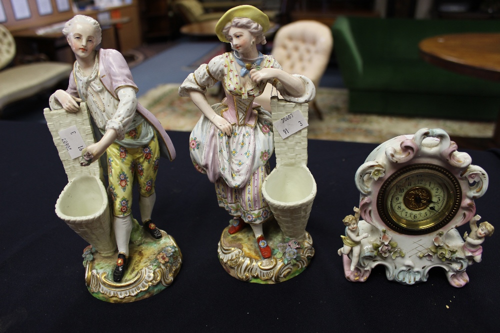 A pair of Continental figural spill vases; and a Sitzendorf clock (3)