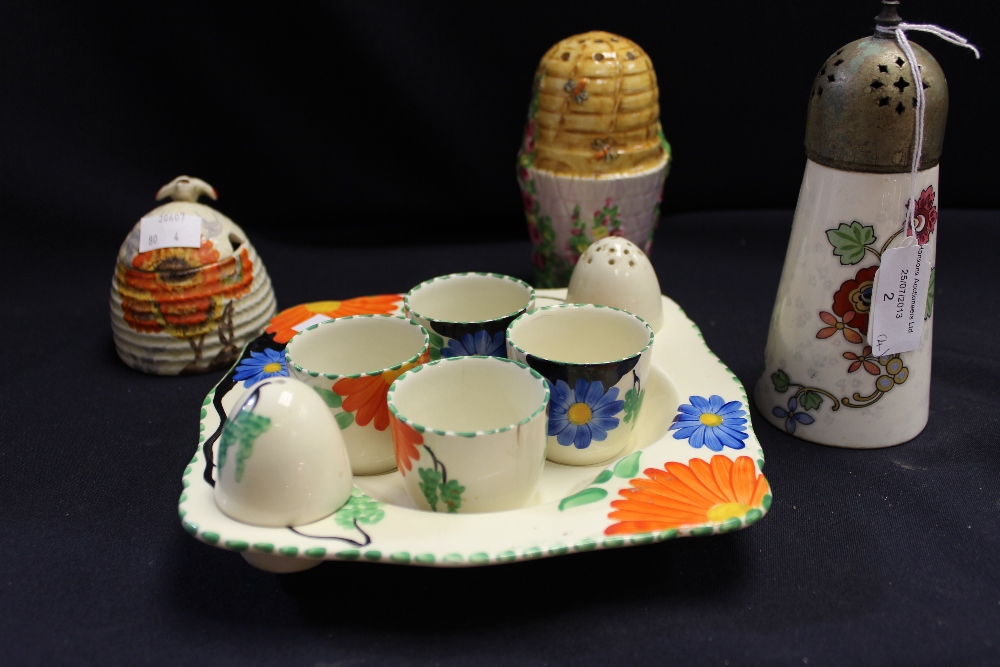 A Clarice Cliff Bizarre beehive jam pot and cover; a Grimwade sugar caster; another sugar caster;