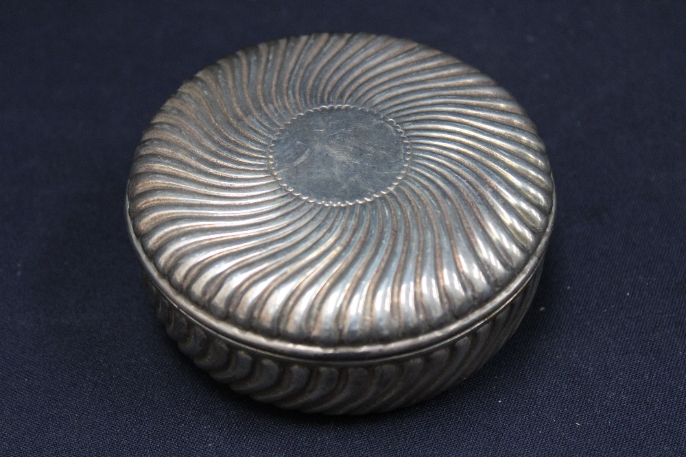A silver circular box and cover, swirling gadroon design, gilt lined