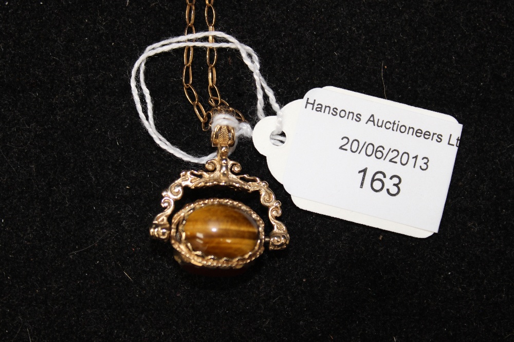 A yellow metal swivel fob, set with tigers eye, etc, on a 9ct gold chain