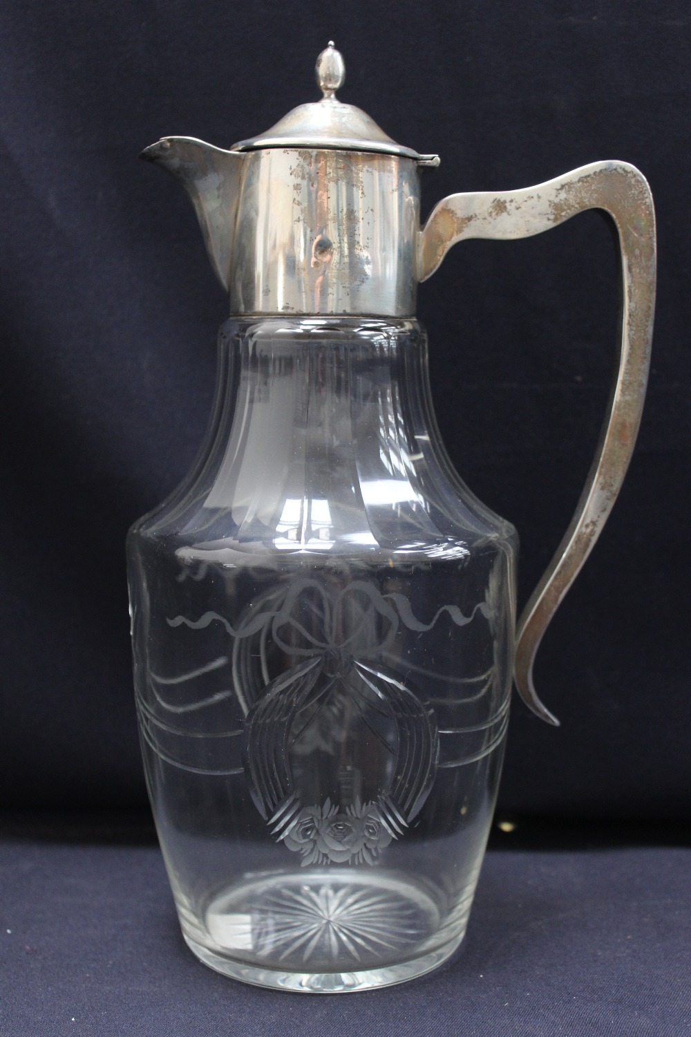 An early 20th century cut glass and silver mounted claret jug, the ovoid body chased with ribbon