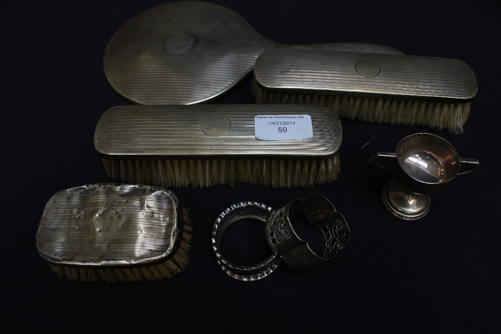 A three-piece silver-backed dressing table set, Birmingham, 1928, two silver napkin rings and a