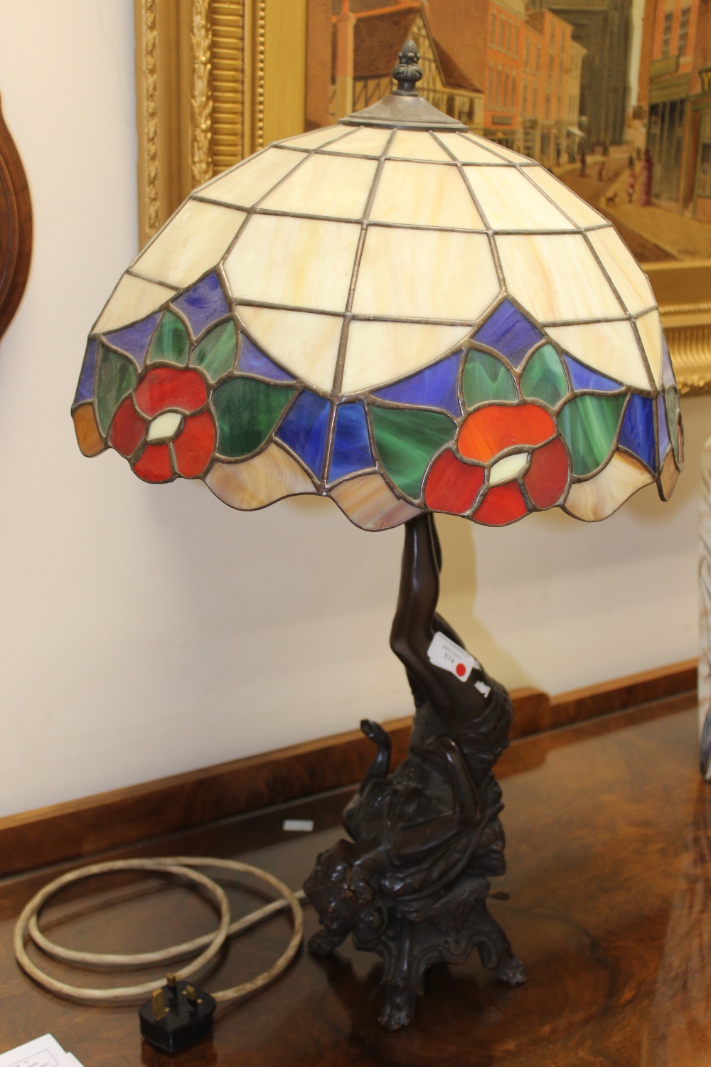 A Tiffany style table lamp, the stand being a lady holding up the shade and fittings