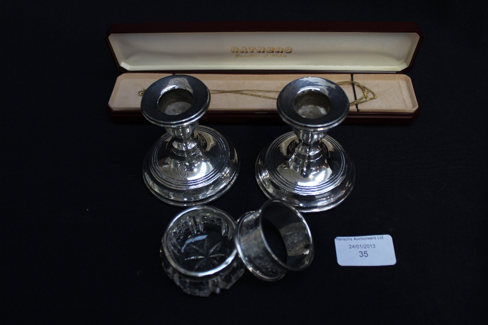 A pair of silver dwarf candlesticks, silver napkin ring, silver-topped cut-glass salt and Ratner`s