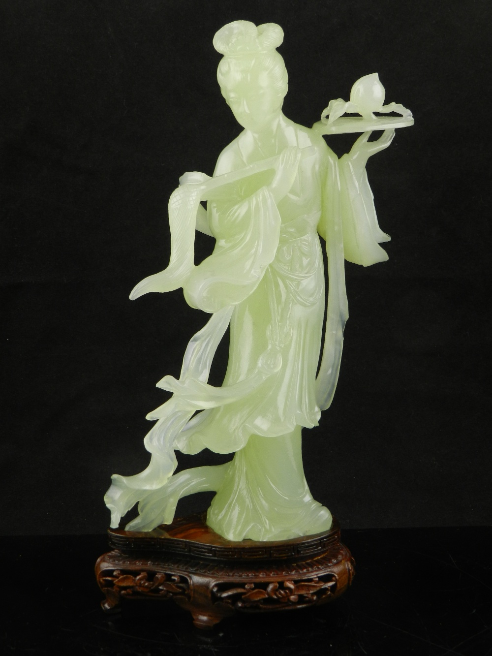 A Chinese jadeite figure of a courtesan holding a fan and a flower on carved and pierced hardwood