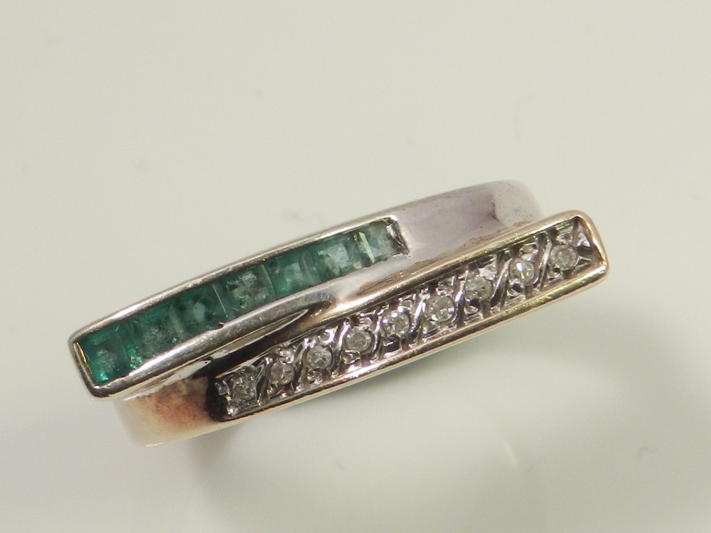 A ladies 9ct gold dress ring, channel and line set with emeralds and diamonds.