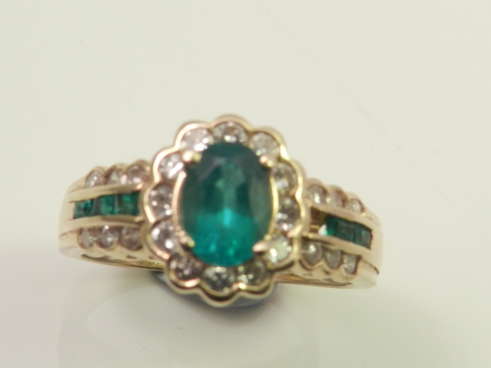 A yellow metal diamond and emerald set cluster ring.