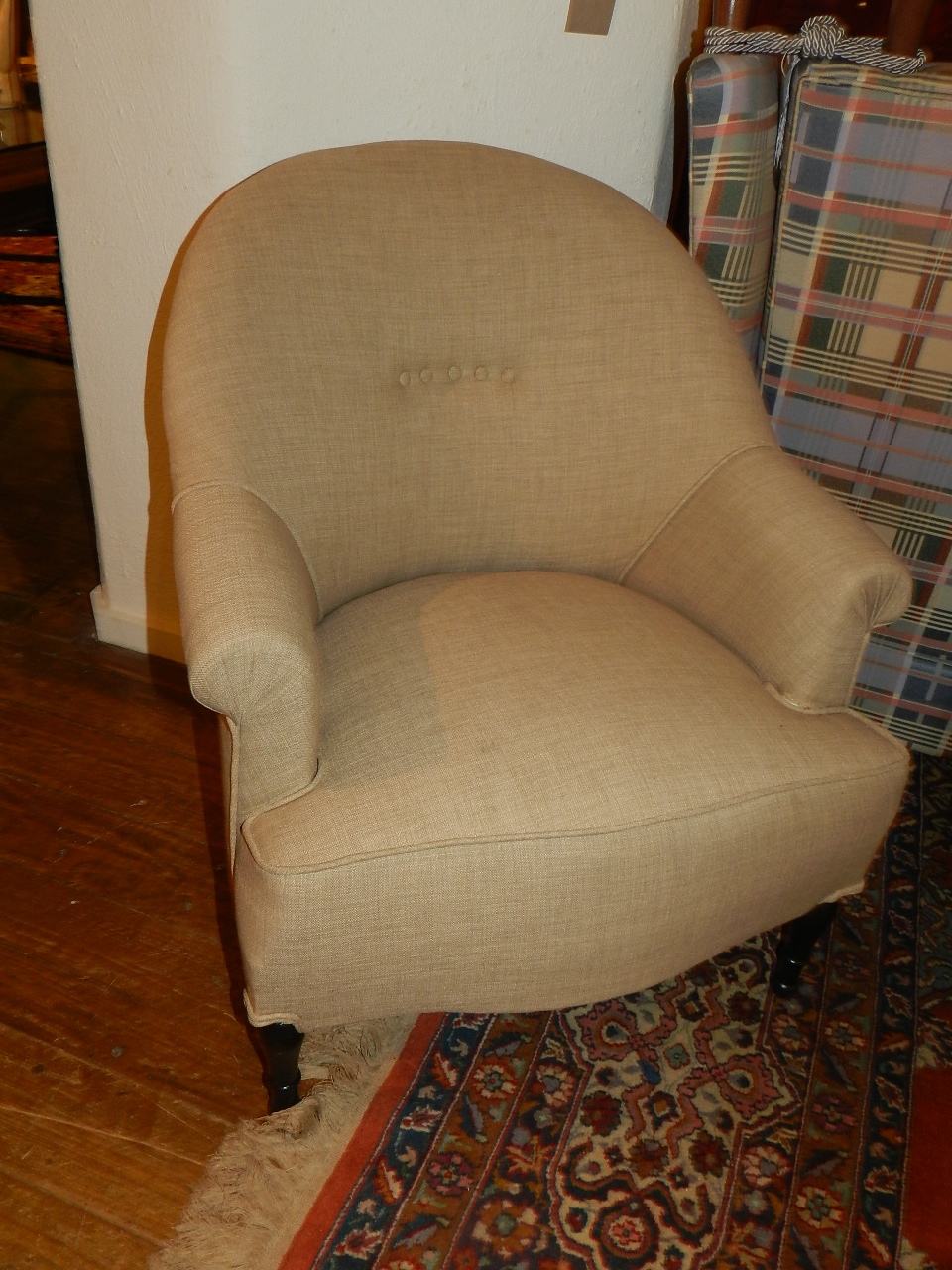 A curved back armchair, upholstered in stone linen on turned legs.