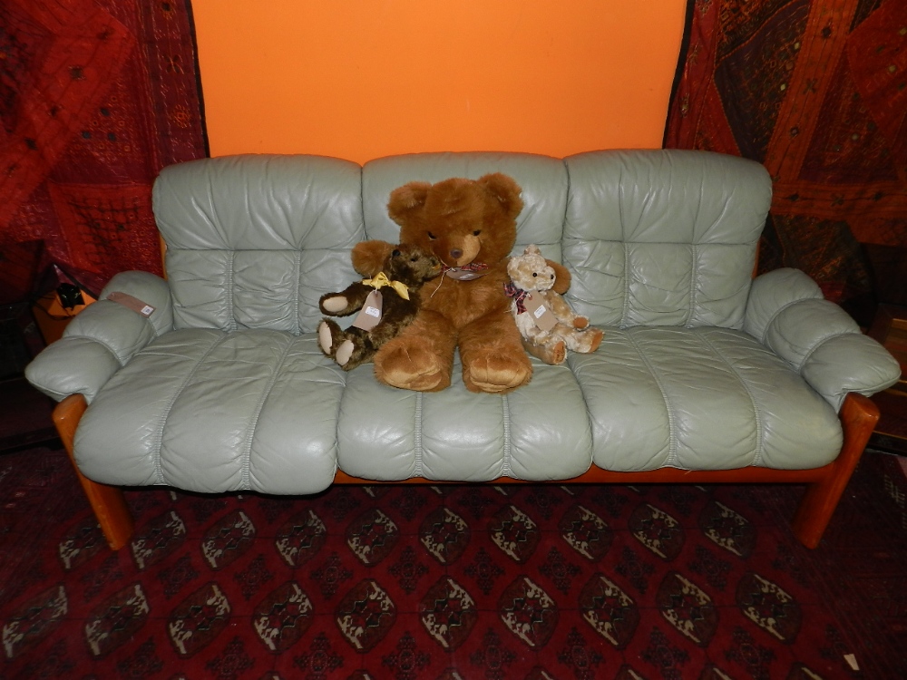 A teak framed three seater sofa, having green leather upholstered cushions.