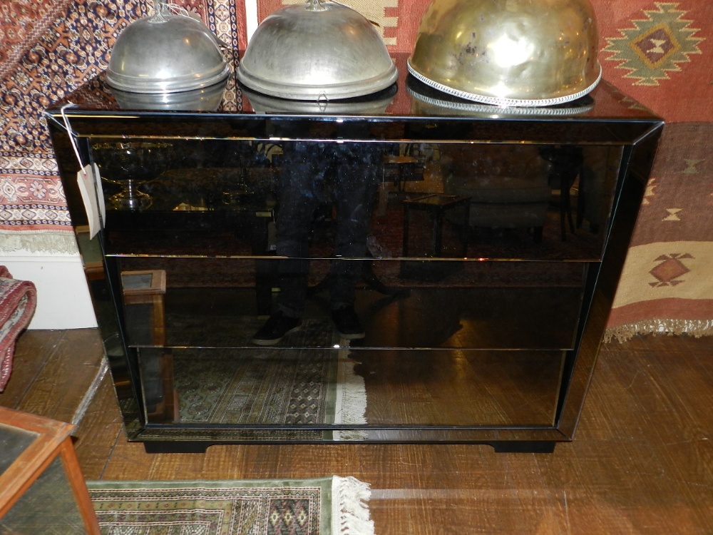 A contemporary smoked mirror clad chest of three long drawers.