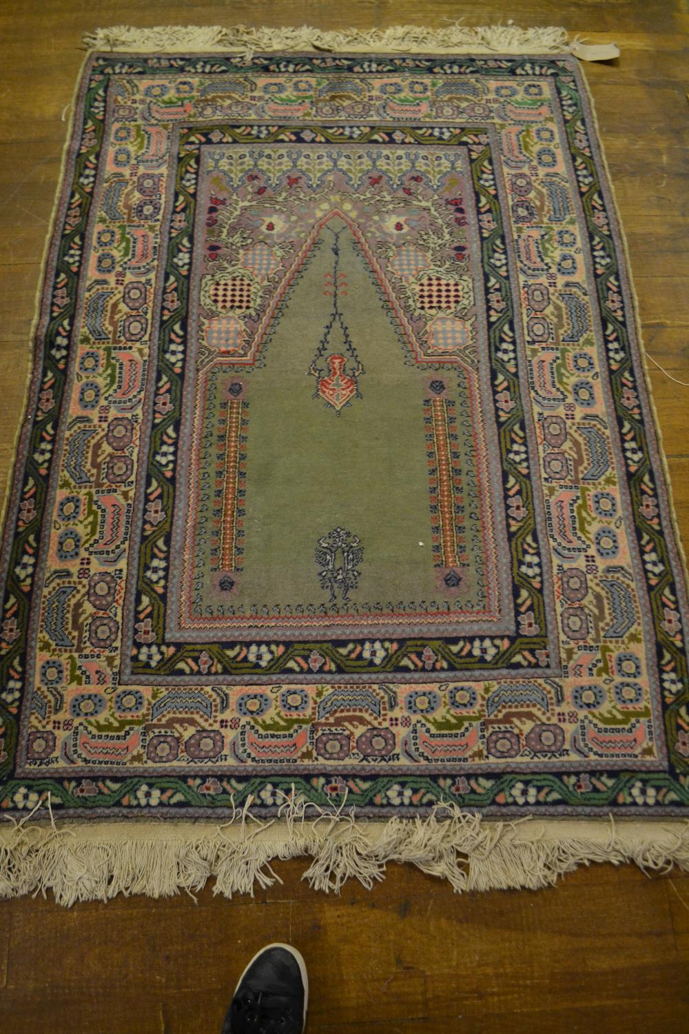 A signed Turkish wool prayer rug, green ground with blue, pink and green geometric and organic