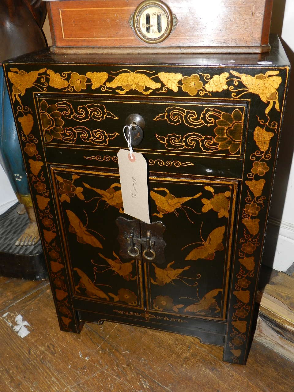 A Chinese black lacquered side cabinet, parcel gilded with butterflies and scrolling foliage, fitted