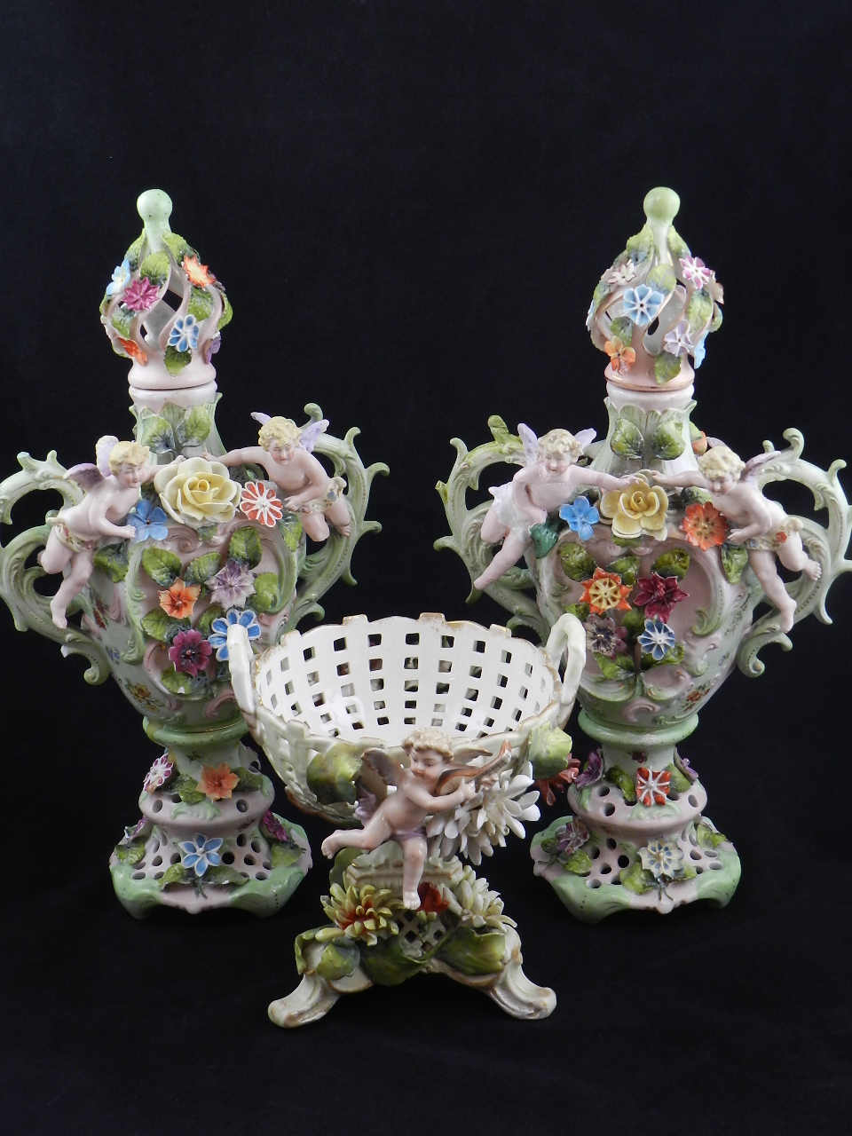 A pair of 19th century porcelain vases with covers, festooned with flowers and putti, together