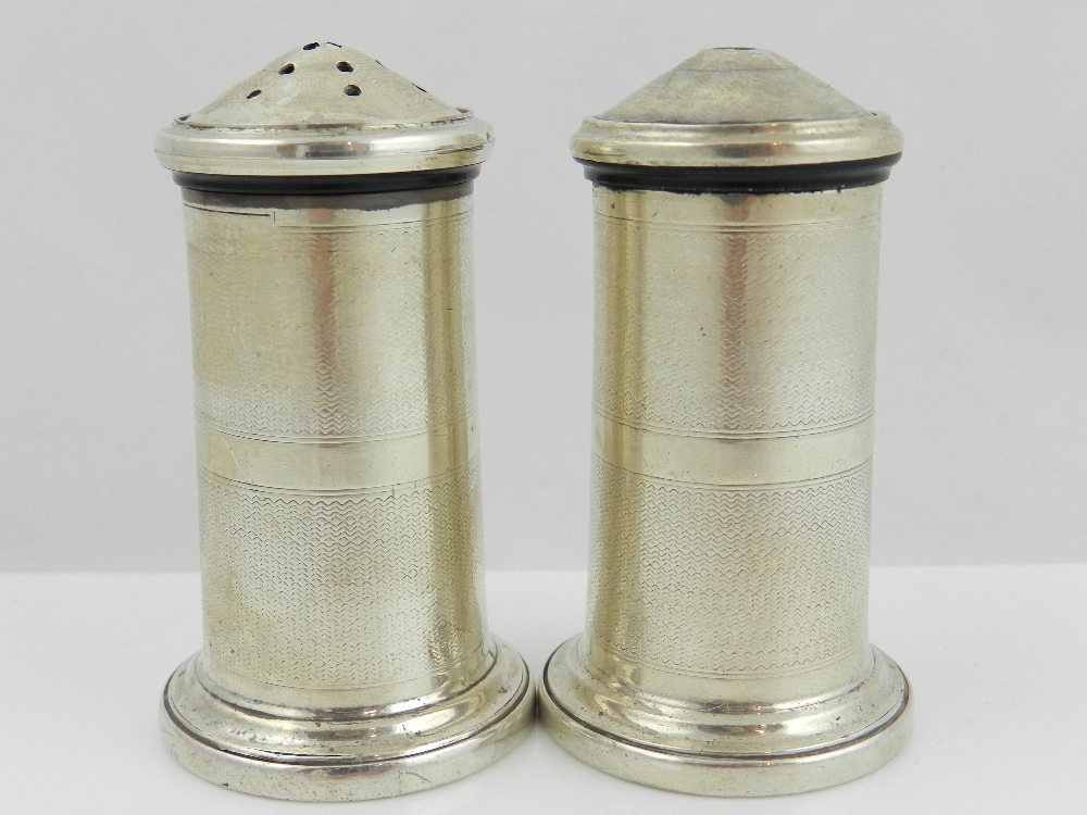 A pair of Art Deco white metal condiments of cylindrical form with engine turned decoration,