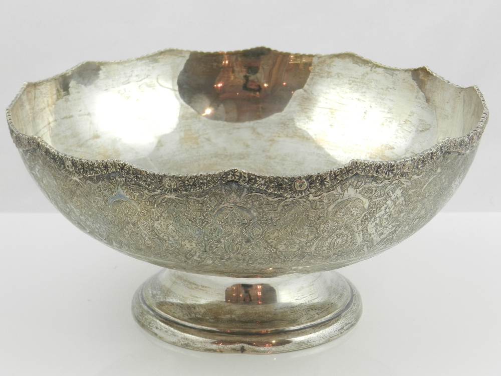 A Persian circular white metal bowl, profusely decorated with stylized flowers, leaves and scrolls