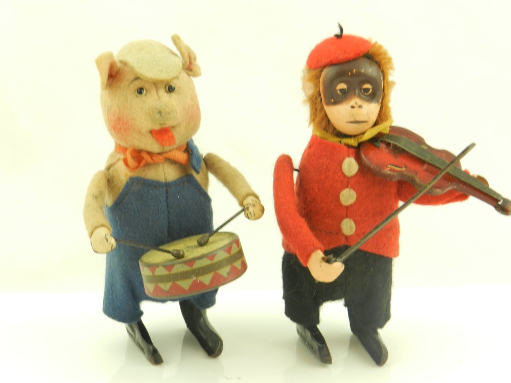 Two wind up Schuco toys, one a pig playing a drum and a monkey playing a violin, both wearing felt