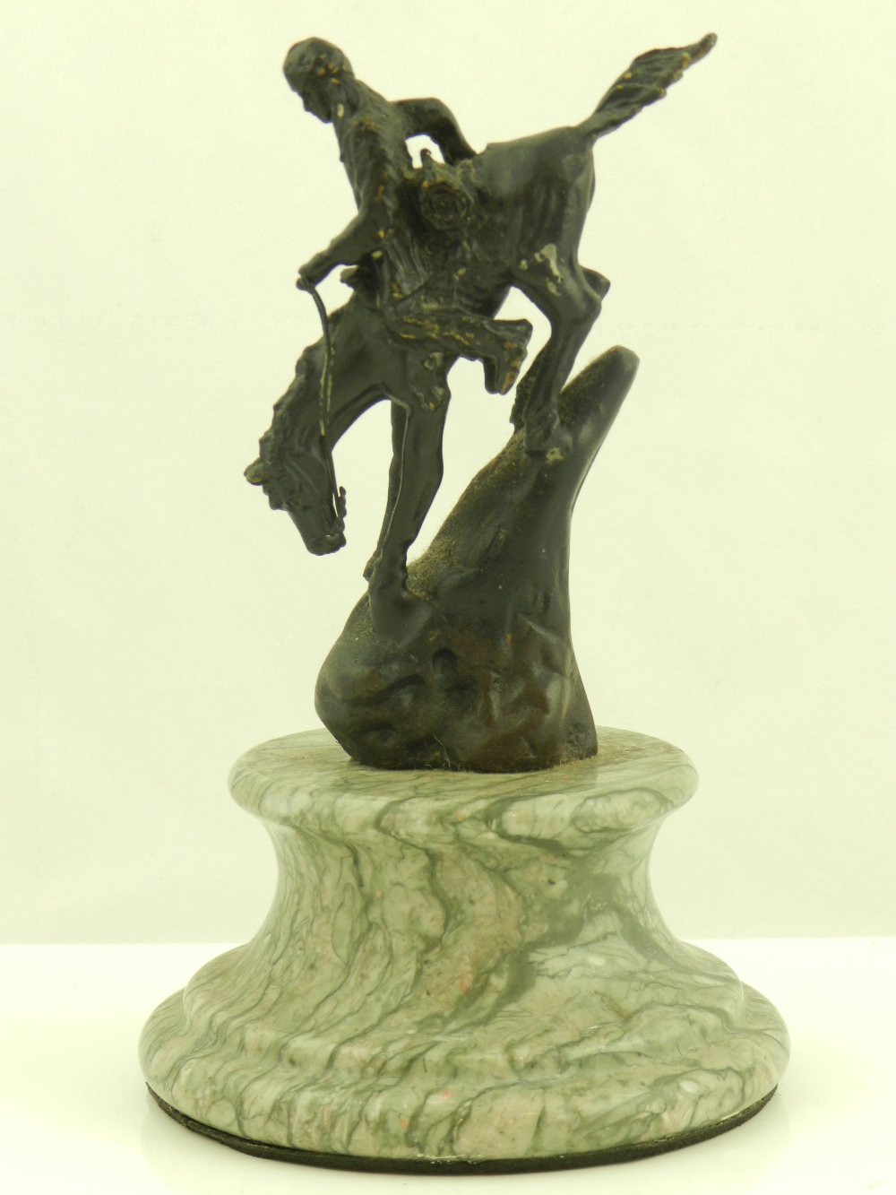 A patinated bronze figure after Remington of a Native American riding a horse down a steep hill,