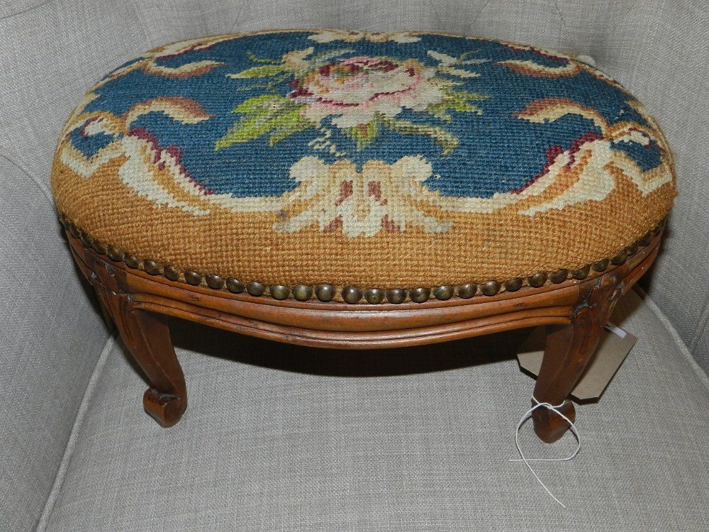 A late 19th/early 20th century French walnut footstool, having foliate woolwork upholstered stuff-