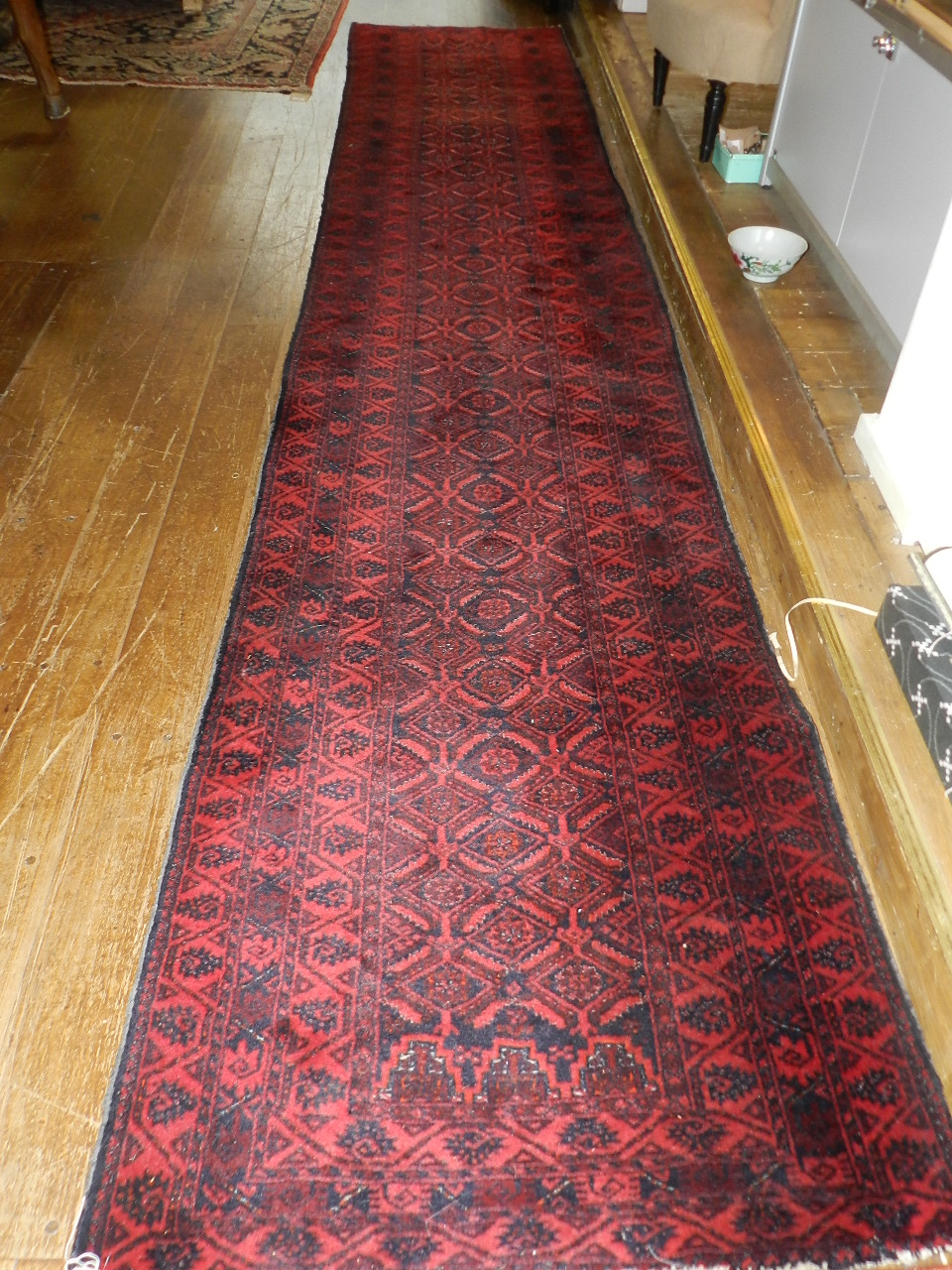 A tribal wool runner of interlocking geometric forms against a maroon ground.