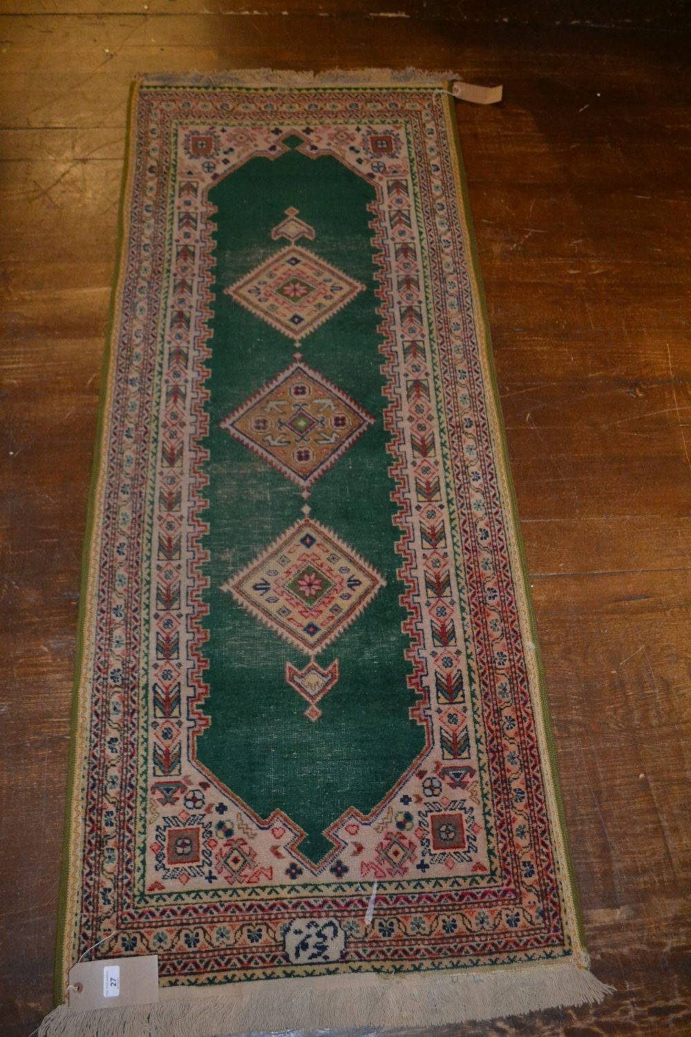 A Persian wool carpet, red and cream geometric medallions to the centre against a green ground, with