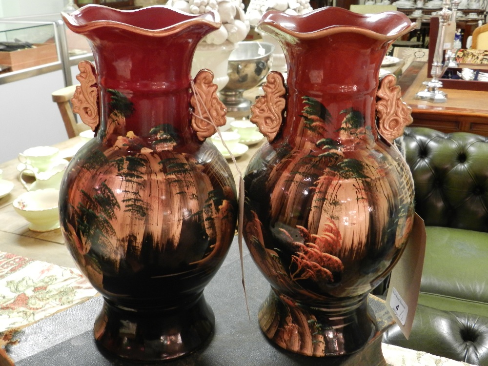 A pair of Oriental porcelain vases, with gilt handles, decorated with landscape scenes.