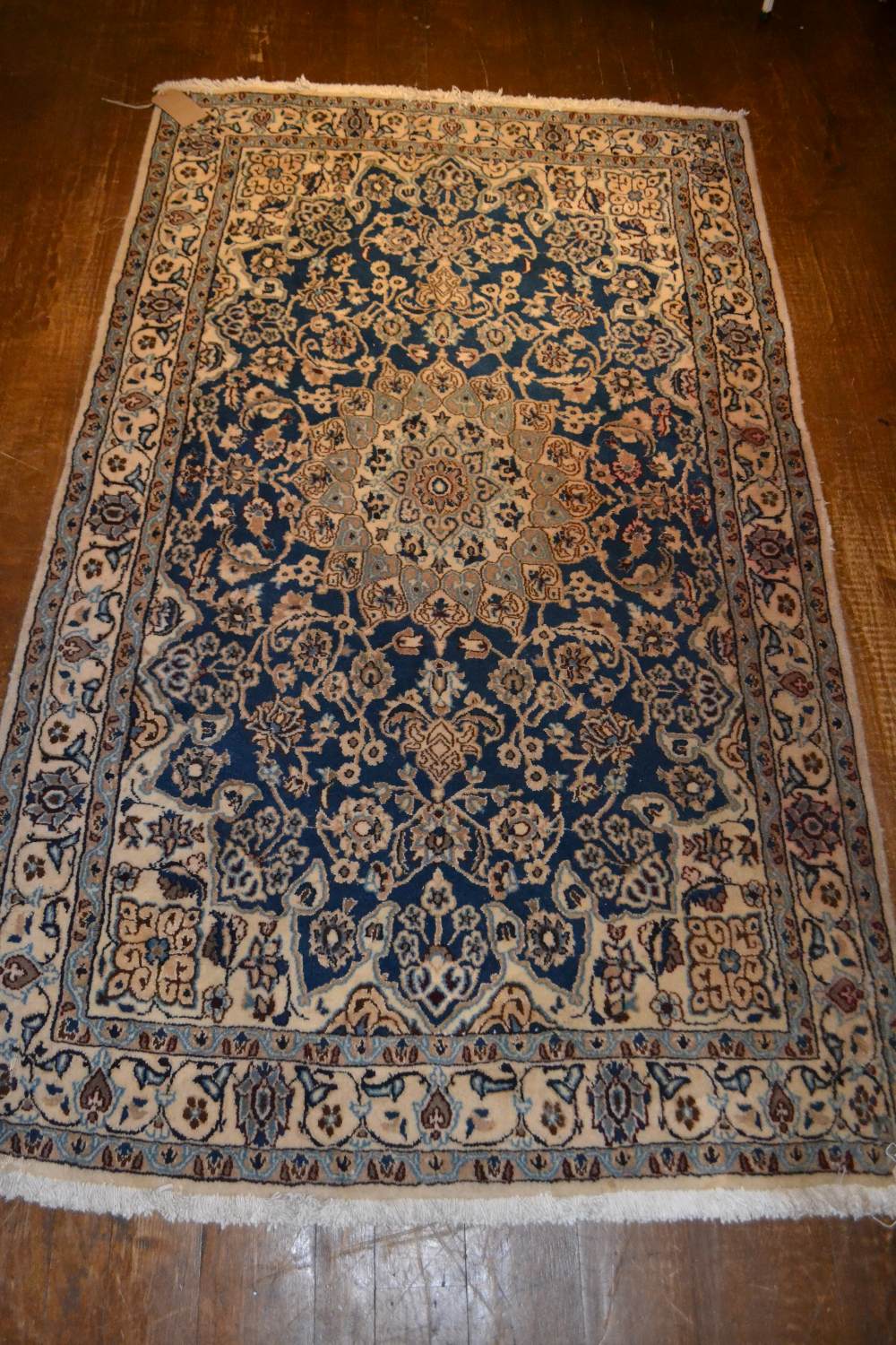 A Persian wool carpet with central oval medallion within a blue ground, scrolling flowers and leaves