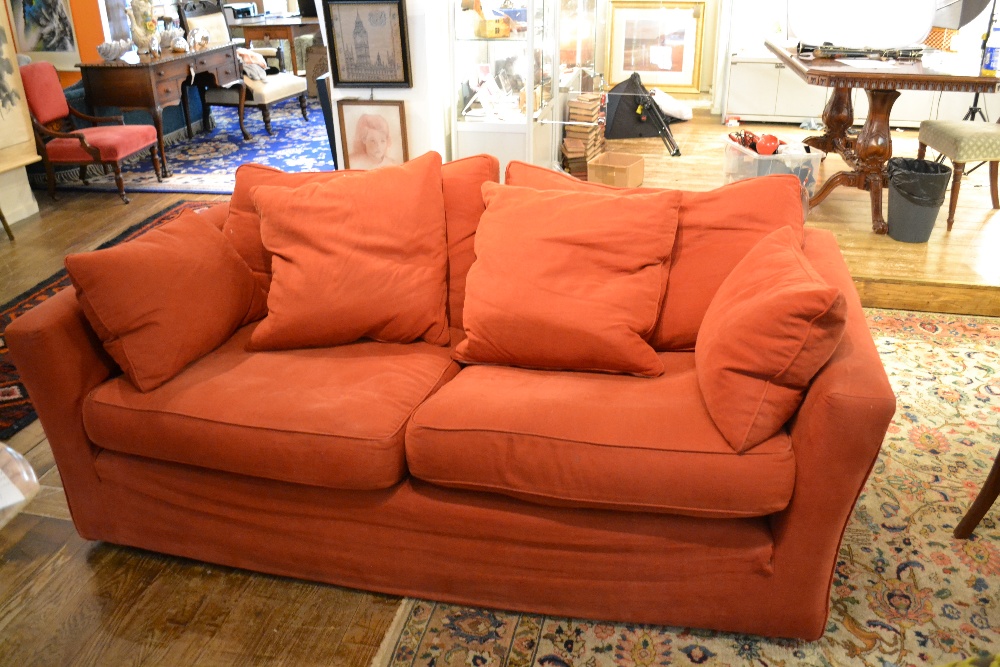 A contemporary oversized two seater sofa upholstered in a burgandy fabric raised on block support.