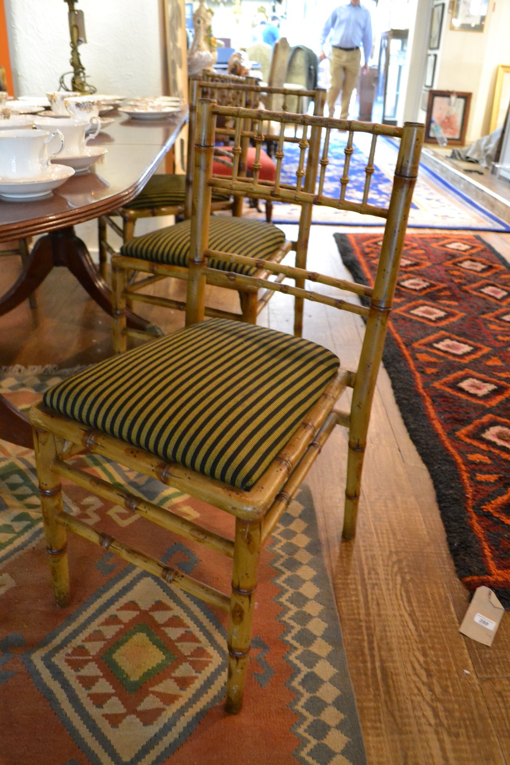 A set of six painted faux bamboo spindle back dining chairs having upholstered drop on seats (from