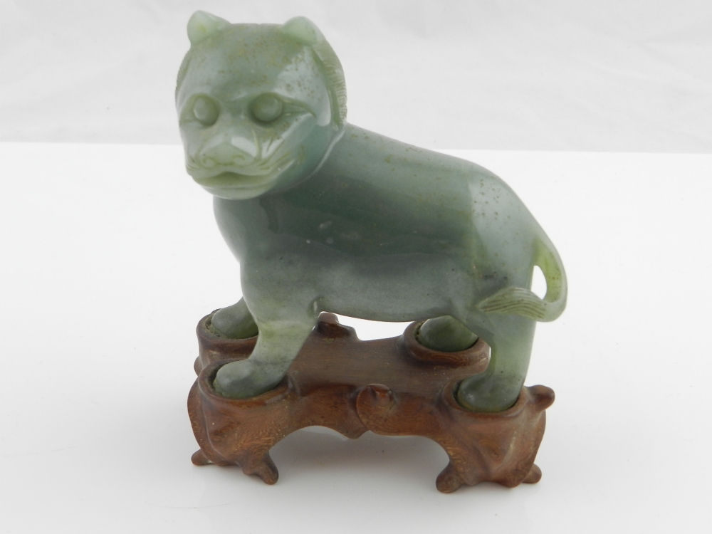 A Chinese carved jade lion on a hardwood base.