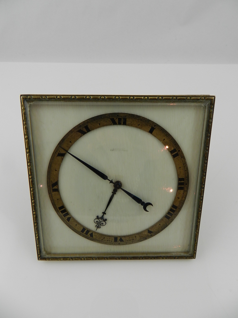 A gilt metal and glass cased eight day mantel clock of easel form having ivory face and gilt metal