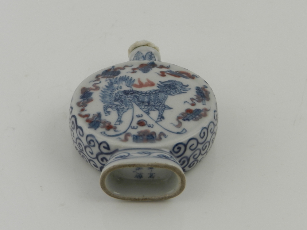 A Chinese porcelain scent bottle of moon flask form decorated with mythical creatures.