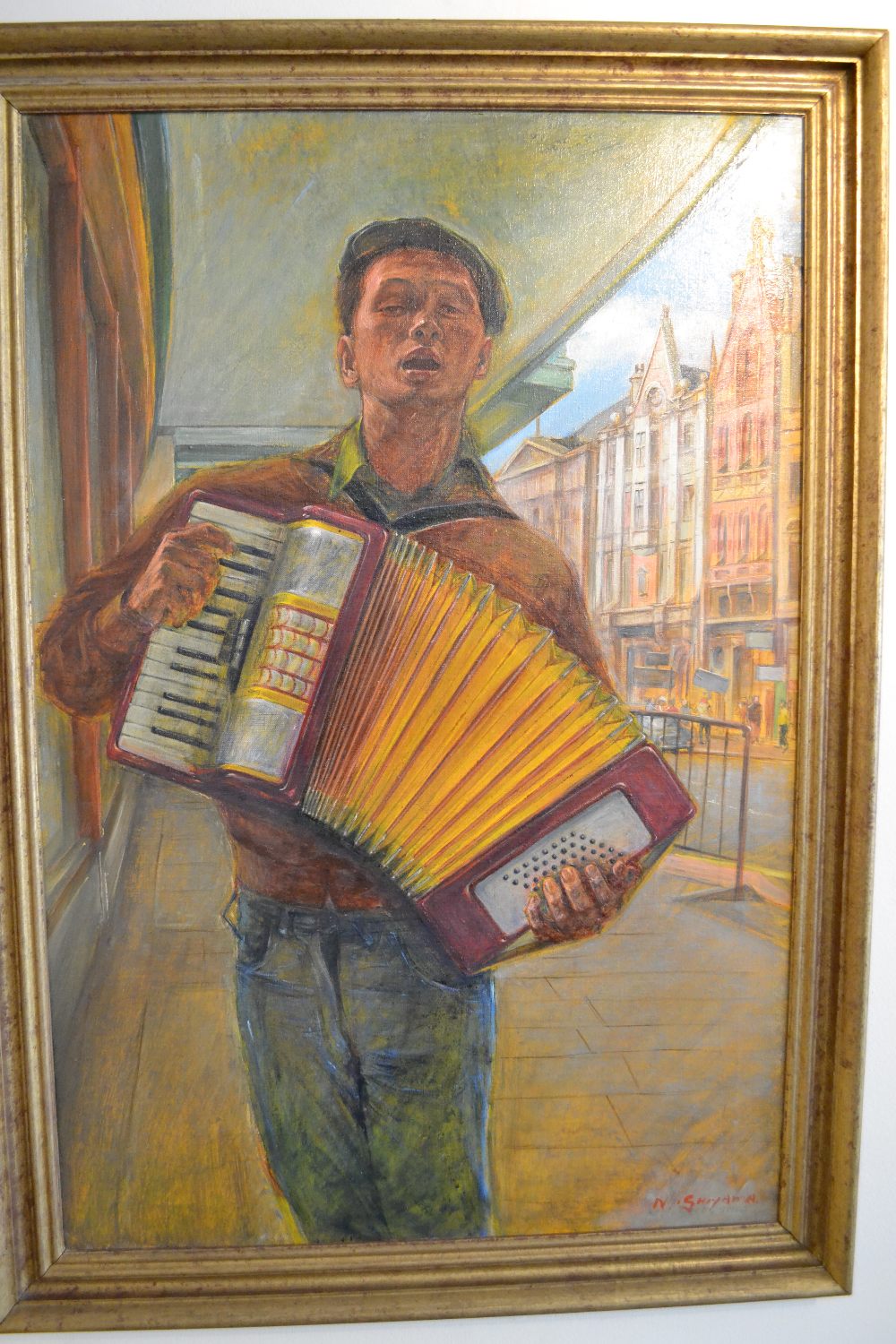 A colourful mid 20th century oil on canvas of an accordion player in a Dutch street scene by